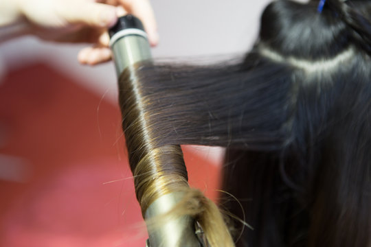 Parrucchiera lavora sui capelli con la piastra calda 