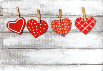 Fototapeta premium handmade toy hearts hanging from a rope on a white wooden background. Valentine 