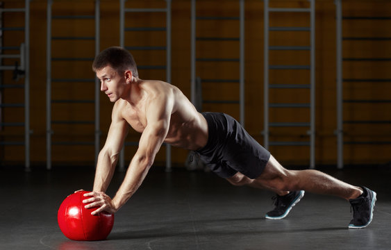 Muscular Man Doing Sport Exercises With Red Medicine Ball.