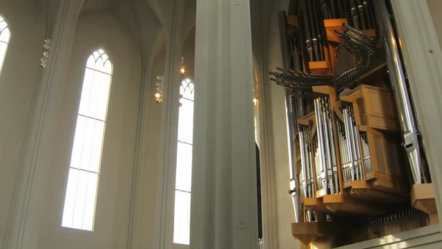 camera moves from narrow windows to huge organ, inside christian church