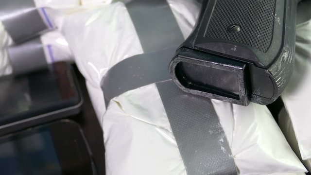 Seized drugs, money, gun, and burner phones on table