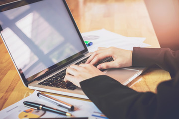 soft focus of woman hand working laptop on wooden desk in office in morning light. vintage effect