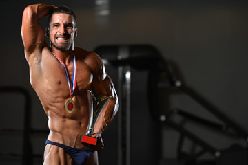 Fototapeta na wymiar Male Fitness Competitor Showing His Winning Medal