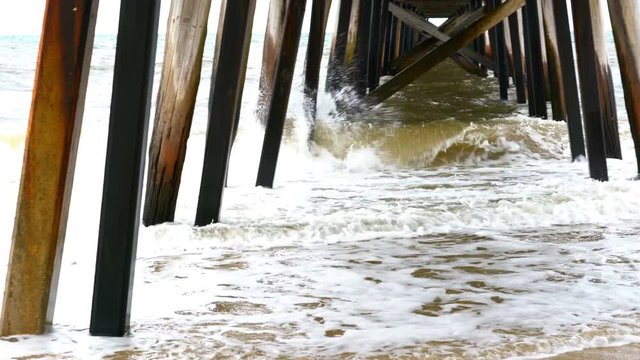 4k Splashing waves at high tide under a jetty pier, taken at Grange Jetty, South Australia, handheld panning.