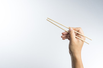 Hand holding disposable wooden chopsticks made of bamboo