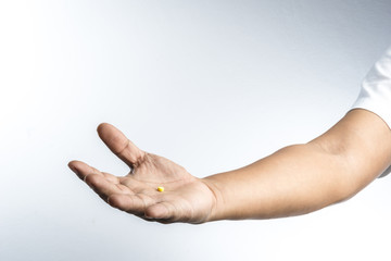 Hand with yellow pill in palm