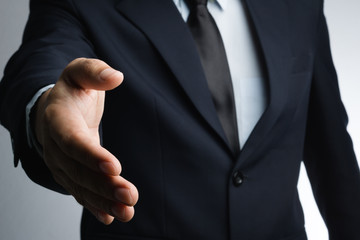 Business man with right hand reaching out for shake hands