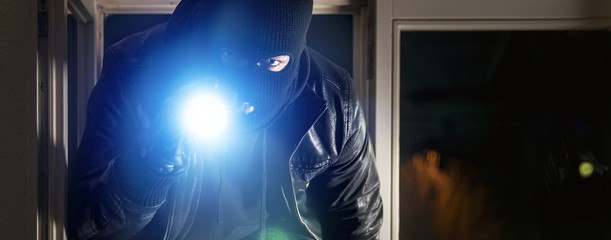 Einbrecher mit Brecheisen und Taschenlampe
