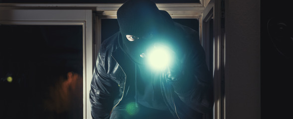 Einbrecher mit Brecheisen und Taschenlampe