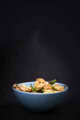 Fried shrimps and asparagus in a bowl on black background