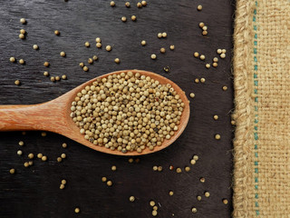 White pepper in wooden ladle on old wooden table and sackcloth background