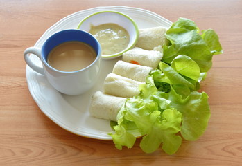 bread roll stuffed bologna and green oak with coffee cup on dish