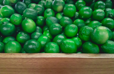 Stack of Limes on Fruit Shelf Stand with Wood for Copy Space at