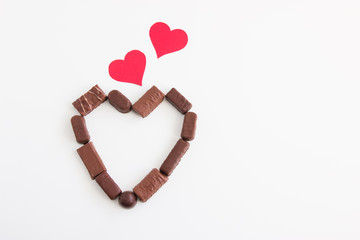 Valentines background with chocolate heart and cardboard hearts.