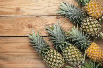  Row of pineapple fruits on wooden table background.