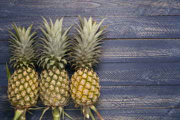  Row of pineapple fruits on wooden table background.