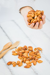 Raw Crispy Almonds on the Hand and White Wooden Board