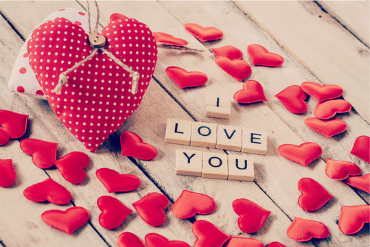 Red heart fabric and wood text of I LOVE You on wooden table bac
