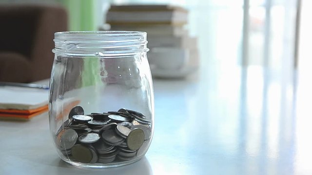 Falling of coins to glass jar concept to saving money