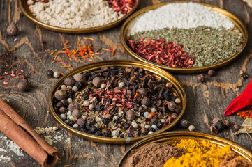 Variety of  spice powders in metal plates on wooden board