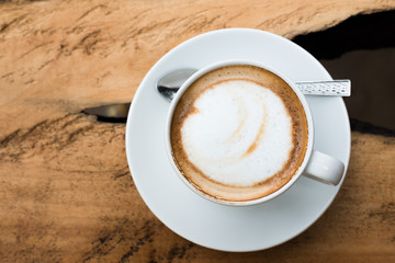 Top view of hot coffee cappuccino cup with milk foam on wood tab