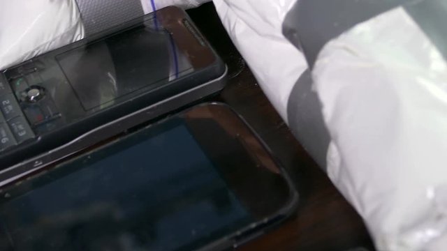 Seized drugs, money, gun, and burner phones on table