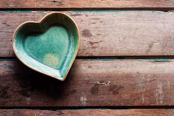 saucer of shaped heart on wood.