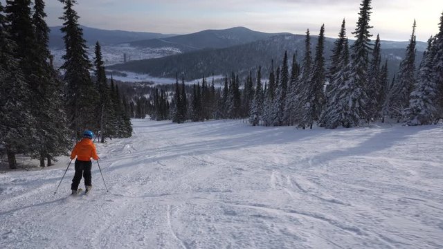 Woman skier is riding down from the top of mountain to snow-covered valley