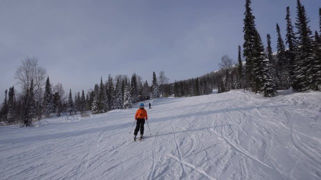 Woman skier is riding slowly from the top of mountain to snow-covered valley