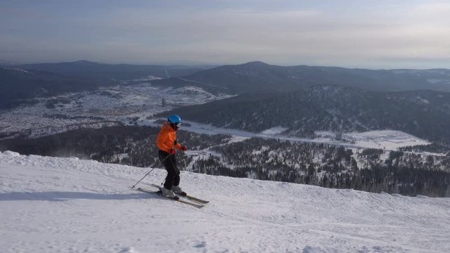 Skier is riding slowly upon winter ski track on the background of mountains