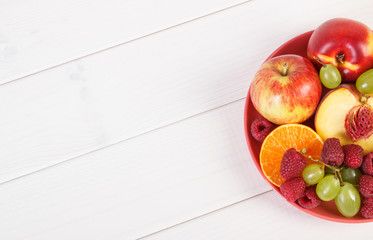 Fresh ripe fruits on plate lying on white boards, copy space for text