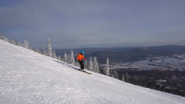 Skier is riding down slowly upon ski track on the background of winter mountains