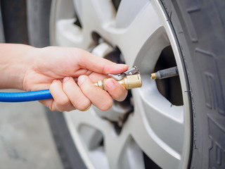 driver checking air pressure and filling air in the tires close up © Siam