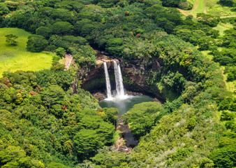 Fototapeta premium Stunning aerial view of Wailua Waterfall near the island capital Lihue on the island of Kauai, Hawaii. Wailua Falls is a 173 foot waterfall that feeds into the Wailua River. Seen from a helicopter.