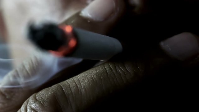Close up of a man smoking a cigarette in the dark
