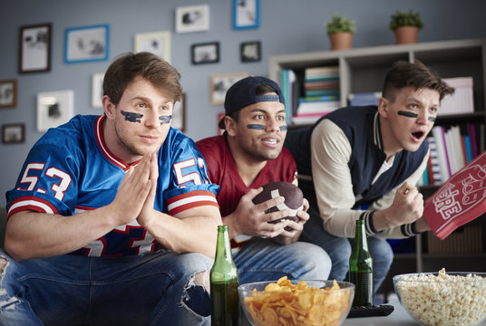 Front view of three men watching American football