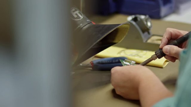 Closeup of male hands soldering printed circuit board assembly with special tool while working in workshop 
