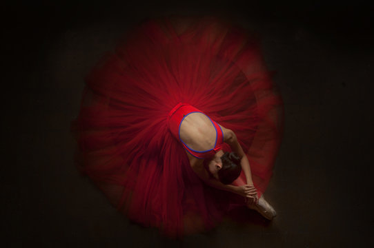 beautiful ballerina woman laying on her knee with beautiful red tutu. image
