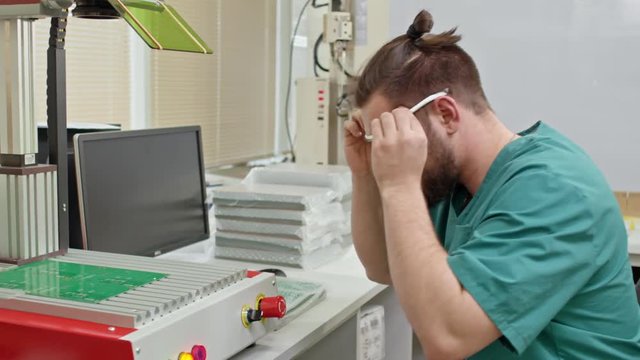 Engineer using testing equipment and computer to check printed circuit boards