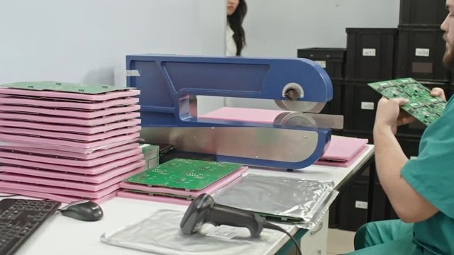 Technician cutting printed circuit boards with special machine at his workplace