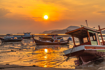 Obraz na płótnie Canvas golden sky in Rawai beach fishing boats are parking on the mug 