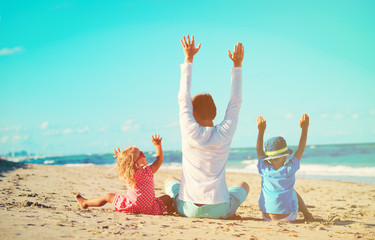 happy father with two kids hands up on the beach