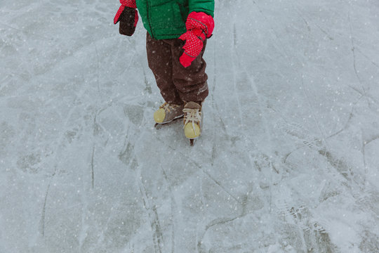 child feet learning to skate on ice in winter