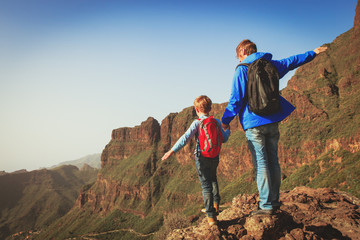 happy father and son hiking climbing in mountains