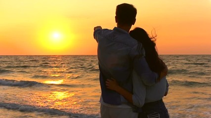 Back view of Young Couple on the beach with sunset on background