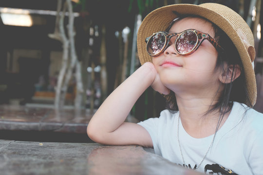 Asian Child Girl Wearing Sunglasses And A Hat Pose Hands Chin