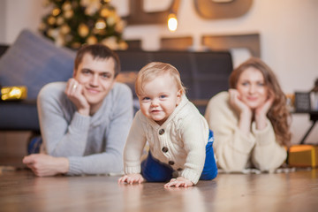 Happy family is lying on carpet tree and smiling