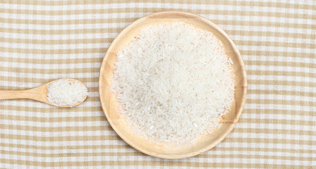 Fototapeta na wymiar Uncooked white rice on wooden plate and spoon on top view 2