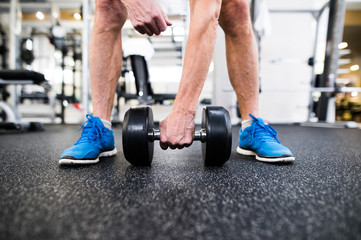 Unrecognizable senior man in gym working out with weights