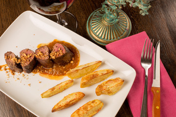 Close up of forest animal steak with potatoes and a glass of win